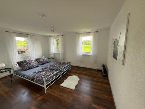 a bedroom with a bed and two windows at Tälealpakahof in Alpirsbach