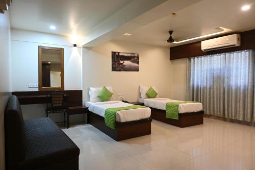 a hotel room with two beds and a chair at Hotel Express Airoli in Navi Mumbai
