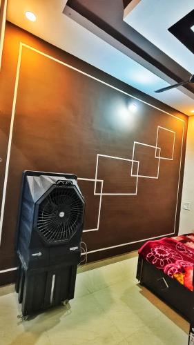 a room with a wall with a bed and a fan at Adiyogi Guest House in Ujjain