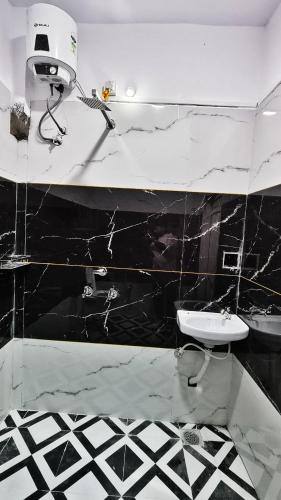 a black and white bathroom with a sink and a toilet at Adiyogi Guest House in Ujjain