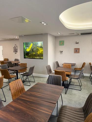 a waiting room with tables and chairs and a large screen at ICON Hotel in Luton