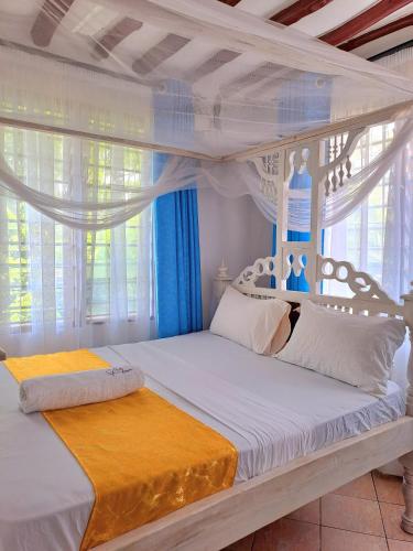 a bedroom with a white bed with a canopy at Elna's Haven Diani Palms - 5min walk to the beach, serene and culinary services in Ukunda