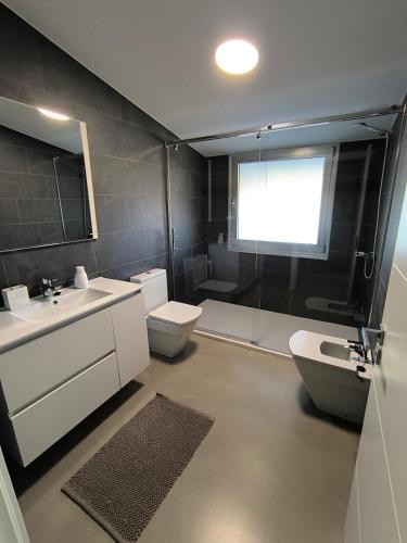 a bathroom with a sink and a toilet and a window at Atico Deluxe en Vimianzo in Toja