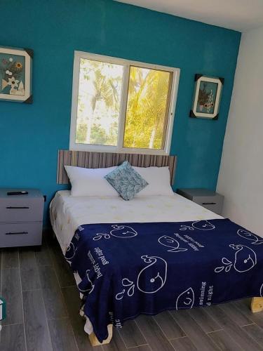 a bedroom with a bed with a blue wall at Xamanai Playa Rincón in Castellalito