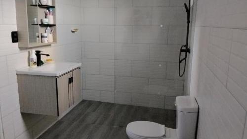 a white bathroom with a toilet and a sink at Xamanai Playa Rincón in Castellalito