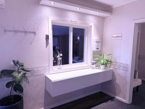 a bathroom with a white sink and a window at Hotel Messeblick in Sarstedt