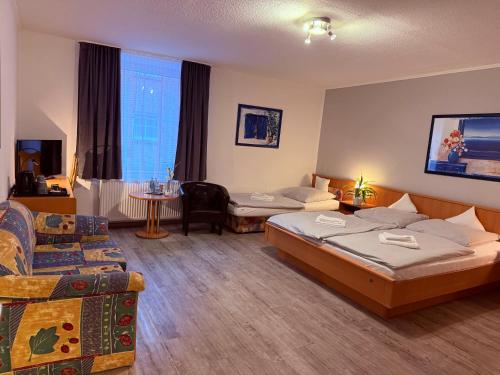 a hotel room with two beds and a couch at Hotel Messeblick in Sarstedt