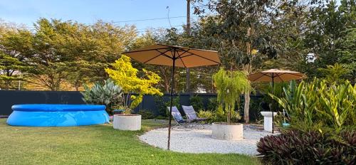 a backyard with an umbrella and chairs and a pool at Bamboo Beach House @ Phang Nga in Thai Muang