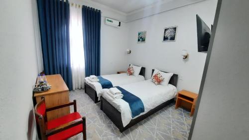 a bedroom with two beds and a table and a desk at Garden Palace Khiva in Khiva