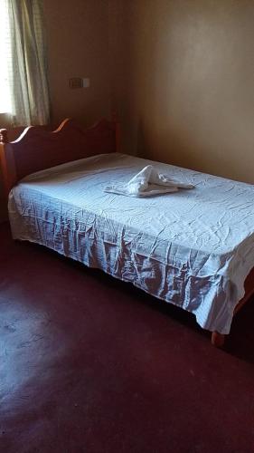 a bedroom with a bed with a white sheet on it at Footprint Baringo in Marigat