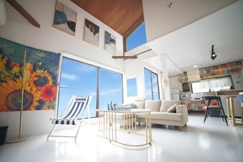 a living room with a couch and a table and chairs at 【マリンブルー風オーシャンビュー】貸切ヴィラ WIFI付/BBQ可能/最大6名/無料駐車場 in Okawa