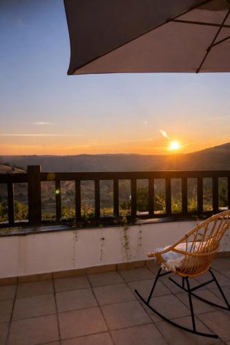 a chair on a balcony with a sunset in the background at Sweet Quintanilha in Quintanilha
