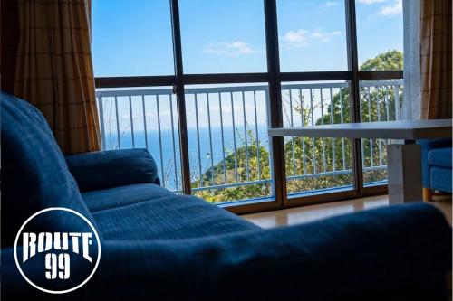 a living room with a blue couch and a large window at 【全室オーシャンビュー 海堪能 抜群景色】貸切一軒家 WIFI付/カラオケ無料/最大８名/無料駐車場 in Okawa
