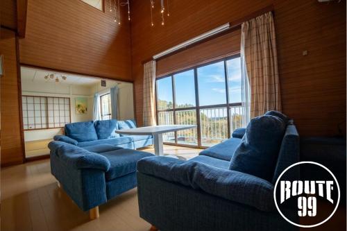 a living room with blue couches and a table at 【全室オーシャンビュー 海堪能 抜群景色】貸切一軒家 WIFI付/カラオケ無料/最大８名/無料駐車場 in Okawa