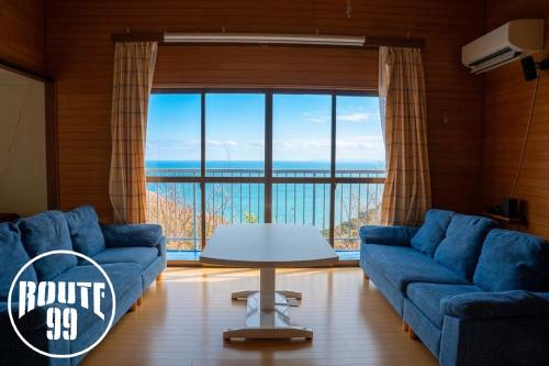 a living room with blue couches and a large window at 【全室オーシャンビュー 海堪能 抜群景色】貸切一軒家 WIFI付/カラオケ無料/最大８名/無料駐車場 in Okawa