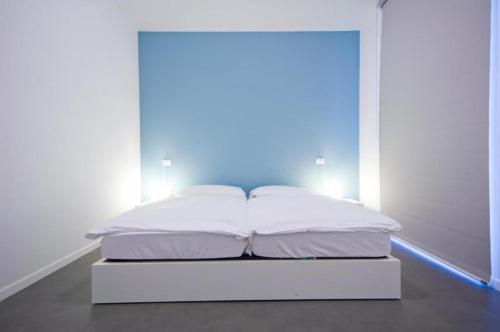 a white bed in a room with a blue light at meckisapartment in Nago-Torbole