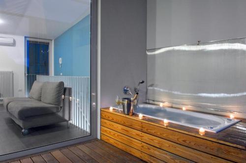 a bathroom with a tub with a chair and a window at meckisapartment in Nago-Torbole