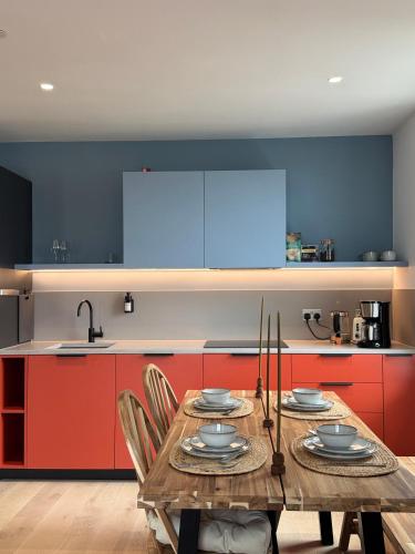 a kitchen with a wooden table and blue and red cabinets at 02 Arena, Specious Apartments in London