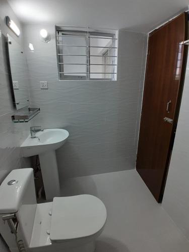 a white bathroom with a toilet and a sink at Chiakunja in Dhaka