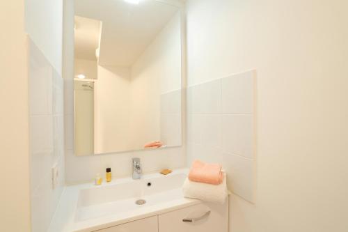 a white bathroom with a sink and a mirror at Résidence Nemea Aix Campus 2 in Aix-en-Provence