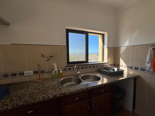 a kitchen with two sinks and a window at Peniche Surf & Sunset House in Peniche