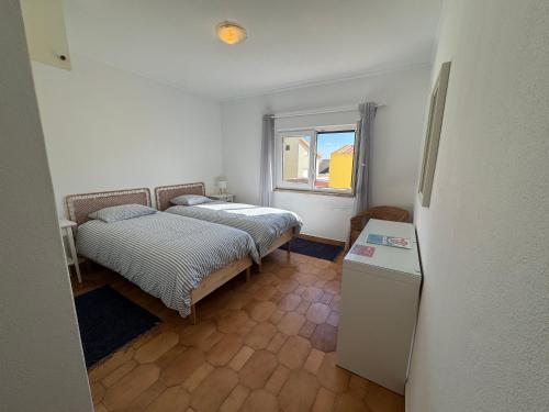 a small bedroom with two beds and a window at Peniche Surf & Sunset House in Peniche