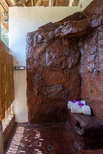 a room with a rock wall with towels and flowers at Elephants Footprint Lodge in Colchester
