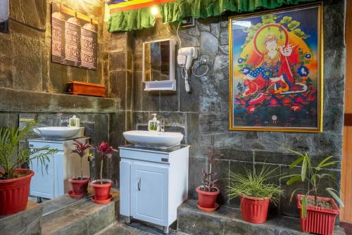 a bathroom with two sinks and a painting on the wall at Mud House Entire Cottage in Dharmsāla