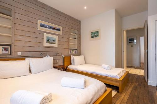 two beds in a room with wooden walls at Creewood - Elie in Elie