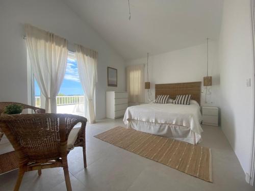 a white bedroom with a bed and a balcony at Menorca Villa Fenicia in Son Parc