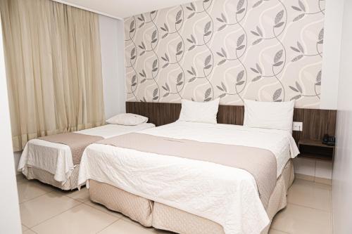 two beds in a hotel room with a wall mural at Premier Pallace Hotel in Araguaína