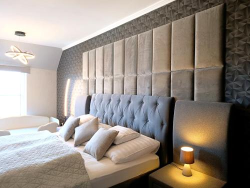 a bedroom with a king sized bed with a padded headboard at Sunshine Residence Silver Apartment in Hévíz