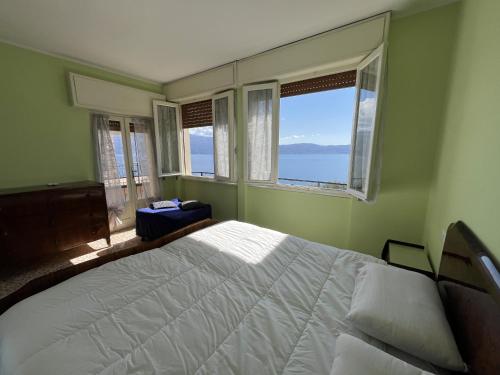 a bedroom with a large white bed and windows at La vista dal borgo in Toscolano Maderno