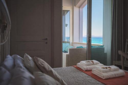 a bedroom with towels on a bed with a view of the ocean at Villa Lilla sulla Spiaggia di San Vincenzo LUXURY in San Vincenzo