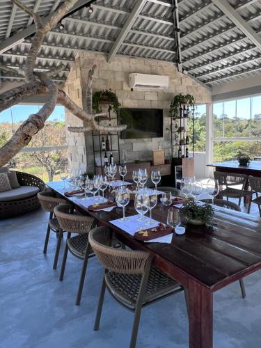 a dining room with a large wooden table with wine glasses at Vinícola Villa Aurum in Corumbá de Goiás