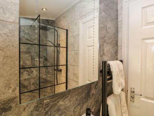 a shower with a glass door in a bathroom at Mere Brook Lodge in Windermere