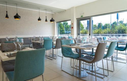 a dining room with tables and chairs and windows at Park Hotel Porto Aeroporto in Maia