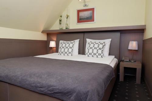 a bedroom with a large bed with two pillows at Garni Hotel Leopold I in Novi Sad