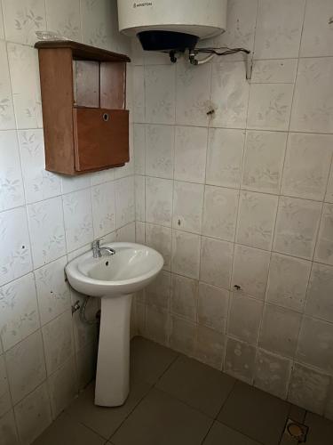 a bathroom with a white sink and a cabinet at Room 11 in Kololi