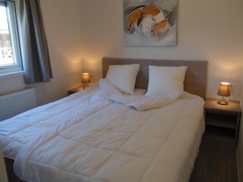 a bed with white sheets and pillows in a bedroom at Moulin de Hotton in Hotton
