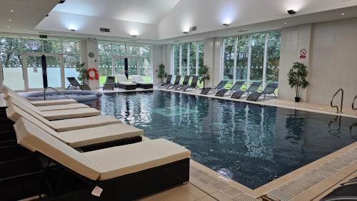 a large swimming pool with chairs in a building at Muthu Clumber Park Hotel and Spa in Worksop