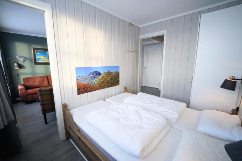 a bedroom with a white bed with a painting on the wall at Bergo Leiligheter in Beitostøl