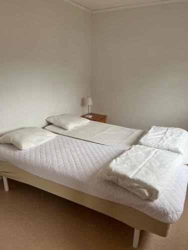 a bed with white sheets and pillows on it at Sjönära stuga i flogned in Åmotsfors