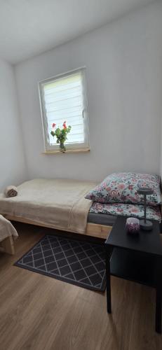 a bed in a room with a window with a flower vase at Domki u Sołtysa in Ciechocinek