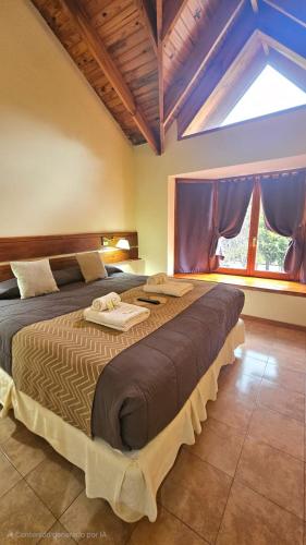 a large bed in a room with a large window at Posada del Ciprés in Villa La Angostura