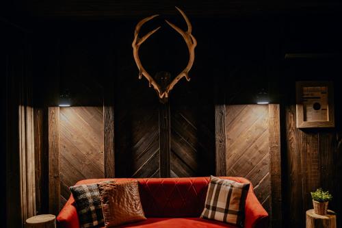 a living room with a red couch and antlers on the wall at Na Gorczańskim Wierchu Chalet, basen, sauna, balia na wyłączność in Rabka-Zdrój