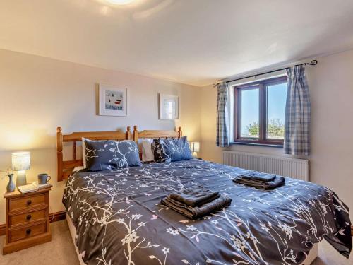 a bedroom with a bed with blue sheets and a window at 3 Bed in Bude oc-corym in Morwenstow