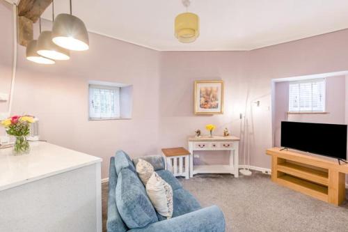 a living room with a blue couch and a television at Hunston Mill Self Catering Dog Stay For Free in Chichester