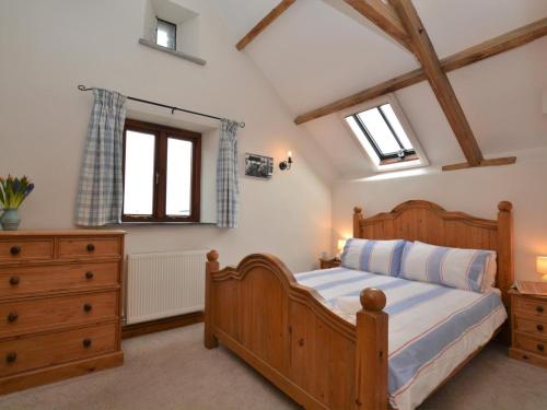 a bedroom with a wooden bed and a dresser and windows at 2 Bed in Bude oc-coryw in Morwenstow