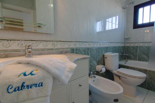 a bathroom with a sink and a toilet and a towel at Villa Corona in Puerto del Carmen
